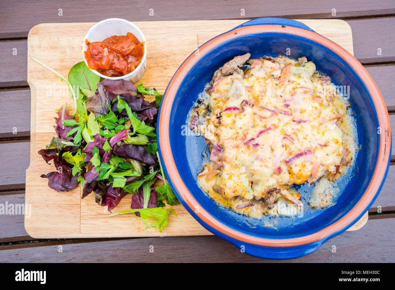 Café pranzo fritto flash bistecca su di patate e verdure con crocchette di formaggio fuso e la cipolla con un lato di foglie verdi e chutney Foto Stock
