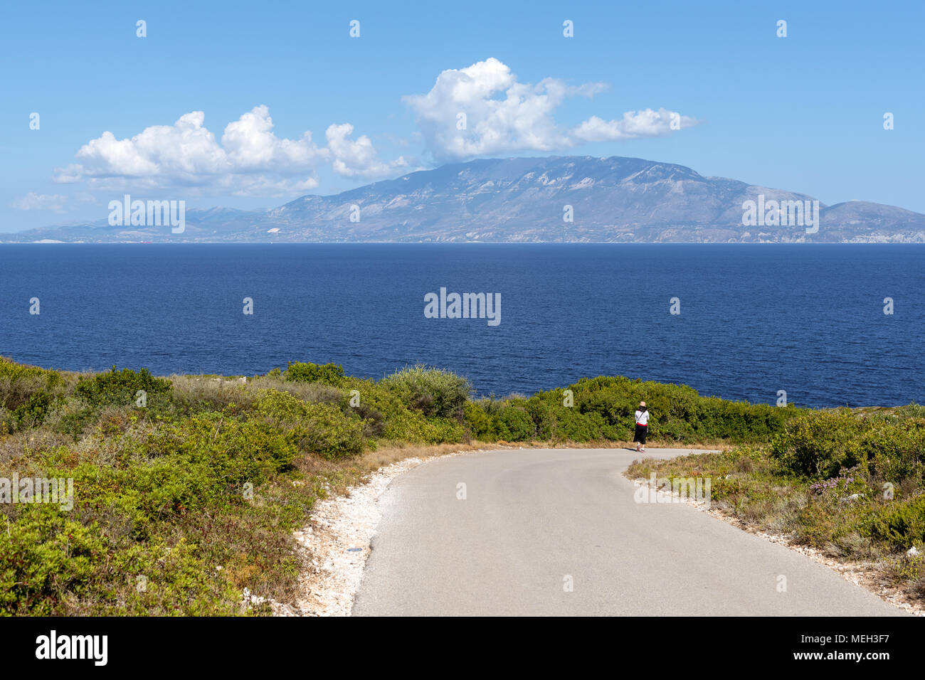 Unidentified turista a piedi lungo una strada a capo Skinari con vedute del mare per l'isola di Cefalonia e Zante, Grecia Foto Stock