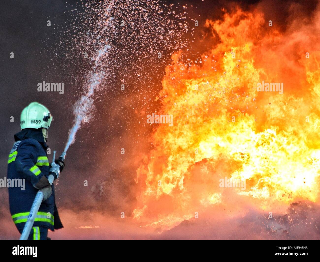 Firefighter combattendo con incendio, rescue cercando di reversibilità. Enormi fiamme bruciato una società di riciclaggio a Tirana, pompiere estinzione di Blaze Foto Stock