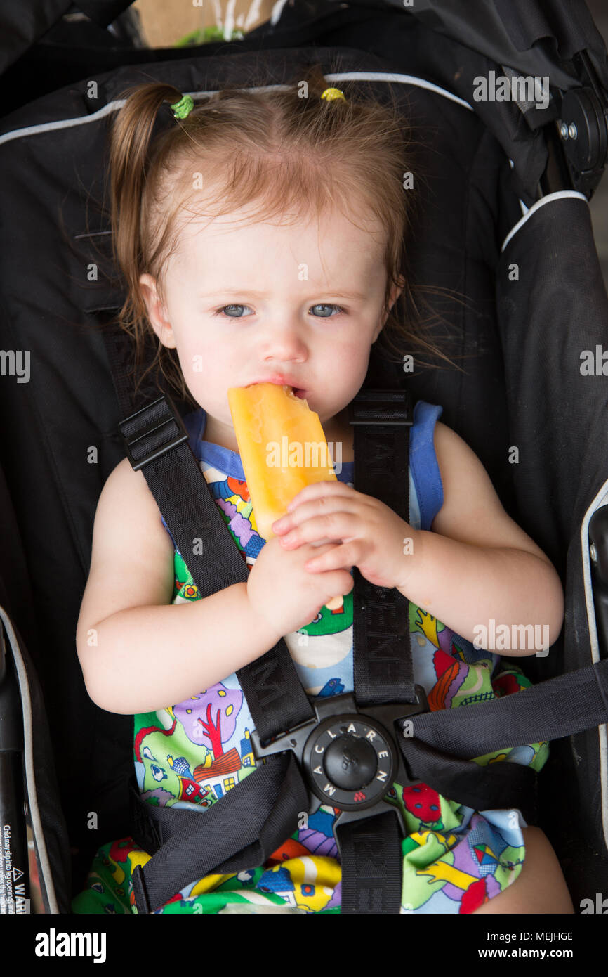 14 mese vecchia ragazza di mangiare un ice per lecca-lecca Foto Stock