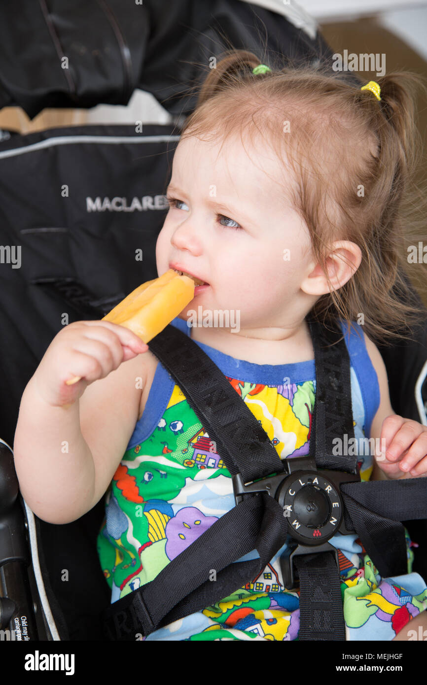14 mese vecchia ragazza di mangiare un ice per lecca-lecca Foto Stock