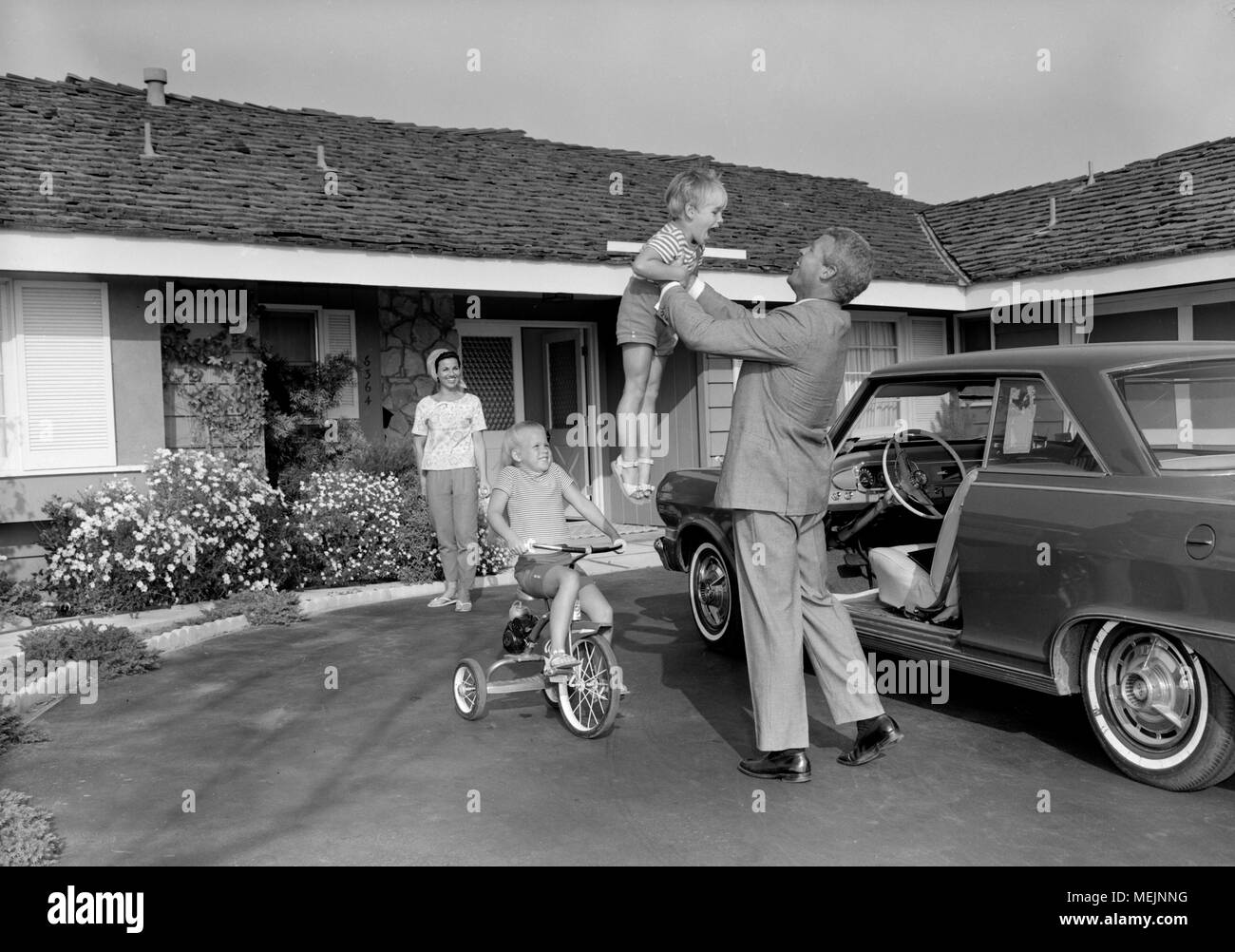 Un perfetto padre arriva a casa dopo il lavoro per una famiglia perfetta nella California del Sud, ca. 1965. Foto Stock