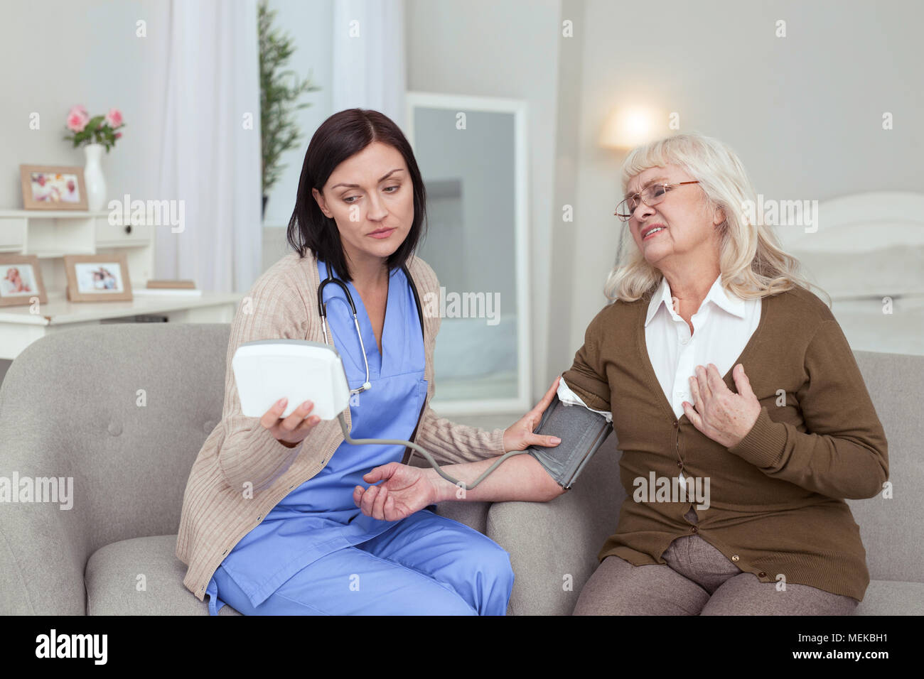 Preoccupato per il caregiver femmina controllando la pressione del sangue Foto Stock