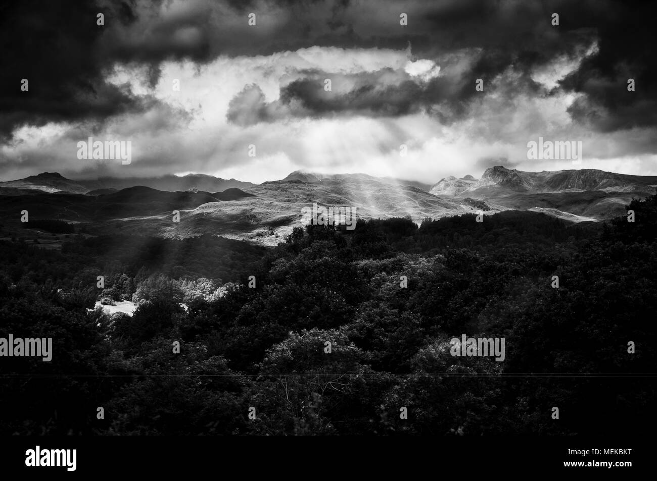 Nuvole temporalesche nel Lake District in Cumbria con raggi di luce che splende su per le montagne Foto Stock