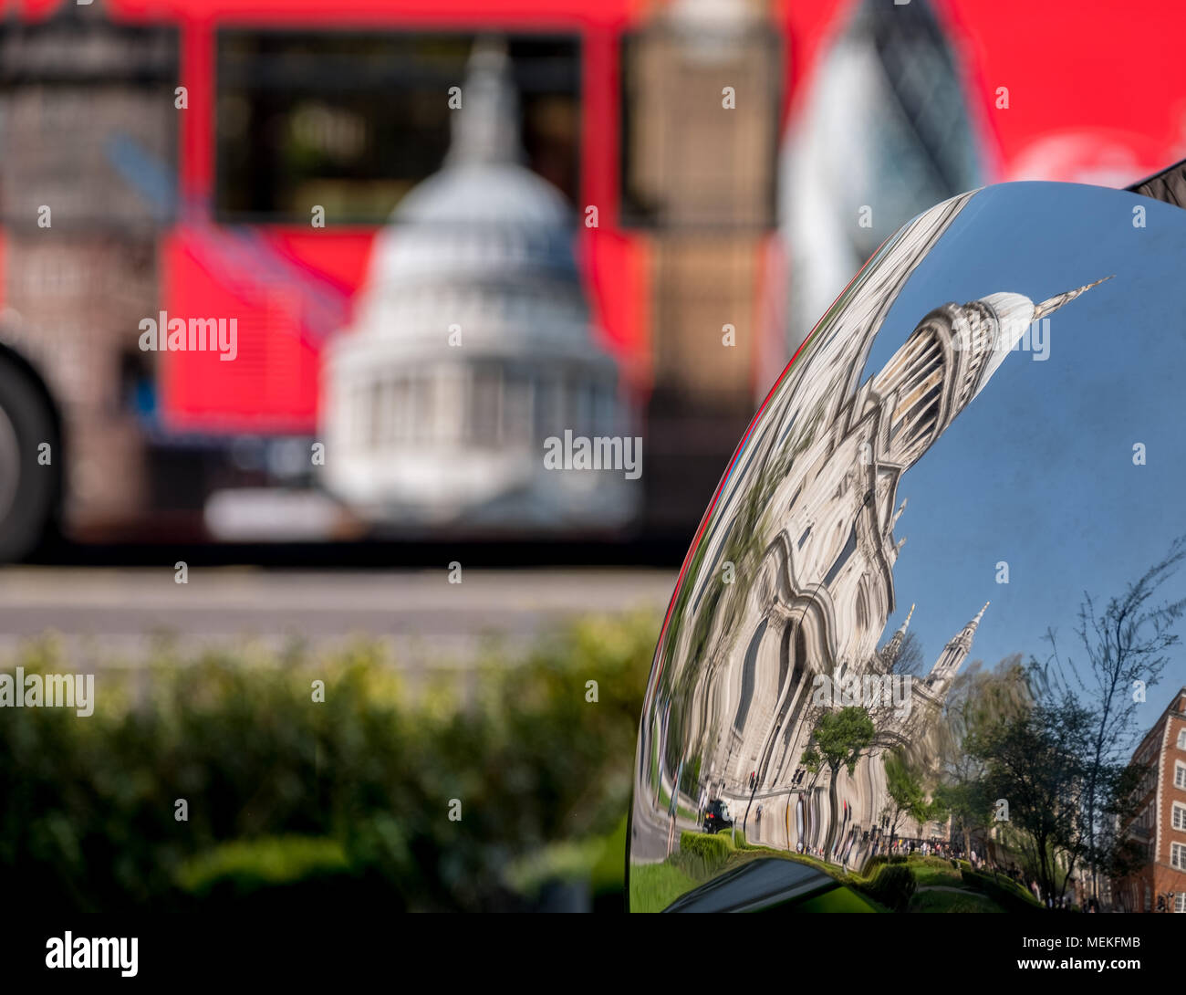 Immagine distorta della Cattedrale di St Paul, Londra UK, riflessa in metallo lucido la superficie della scultura a specchio, offuscata bus rosso in background. Foto Stock