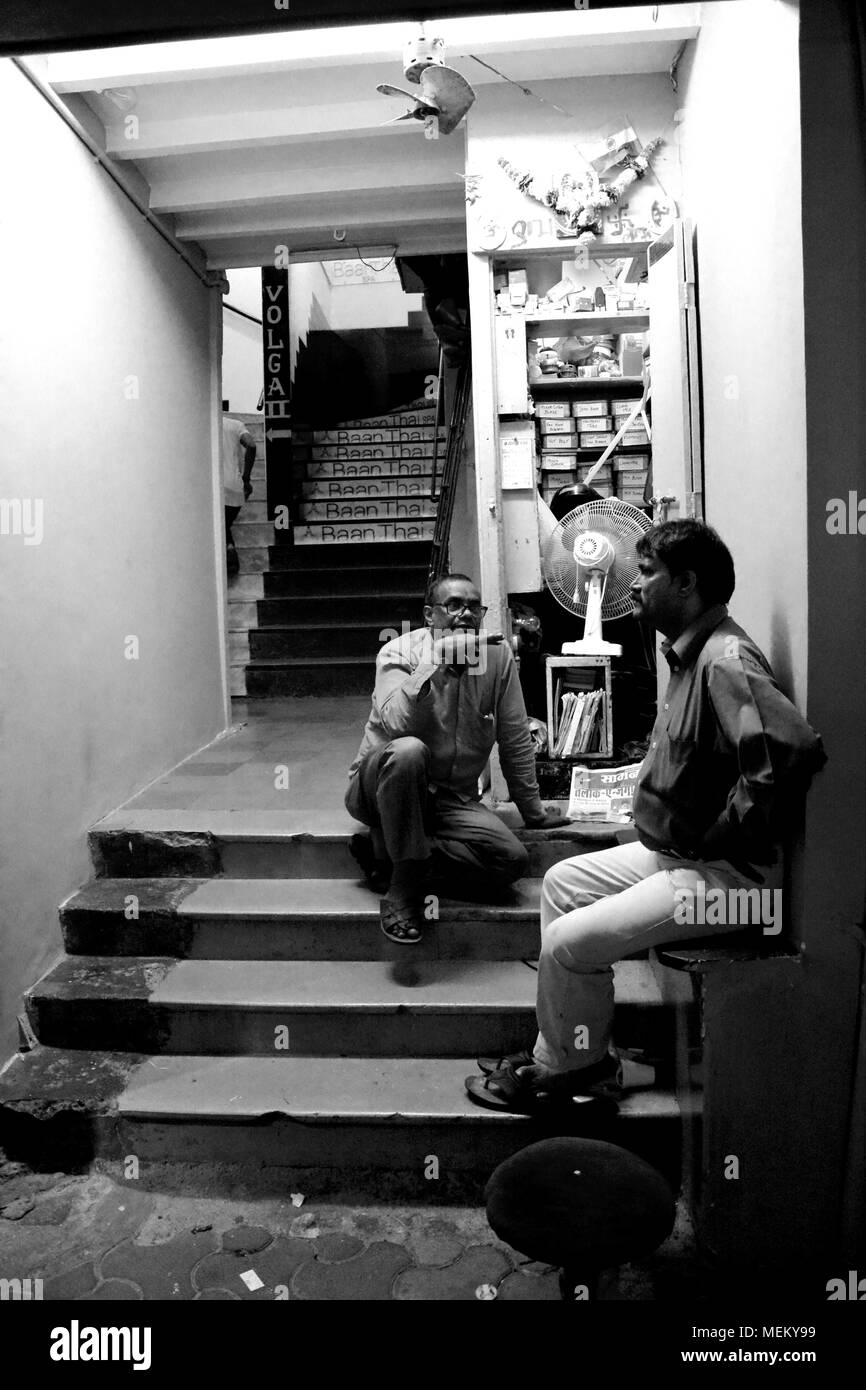 Due uomini avente una conversazione sui gradini, Mumbai, India Foto Stock
