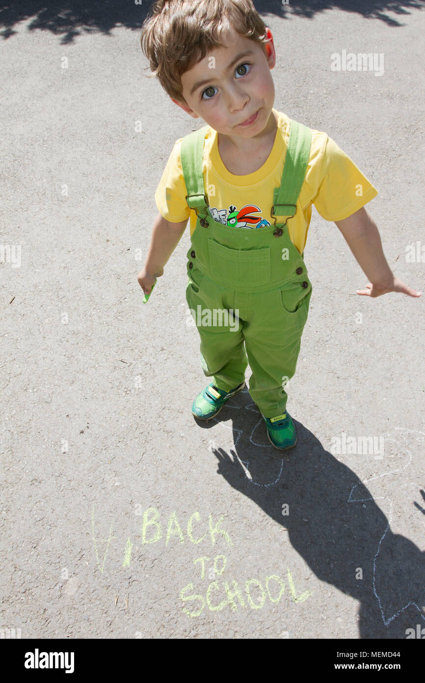 Ragazzo carino scrivere con gessi colorati su un parco giochi per bambini. Capretto piccolo disegna con gessi. Concetto di vacanza. Il concetto di istruzione. Scuola e tempo di divertimento. Giocare Foto Stock