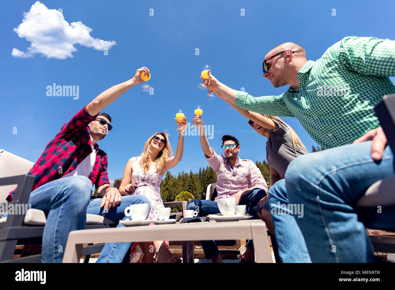 Gruppo di amici tostare i loro bicchieri di succo vicino alla piscina Foto Stock