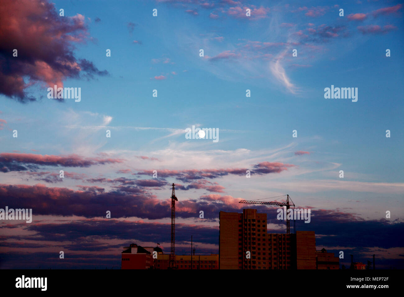 La costruzione di un edificio alto in città al tramonto. Foto Stock