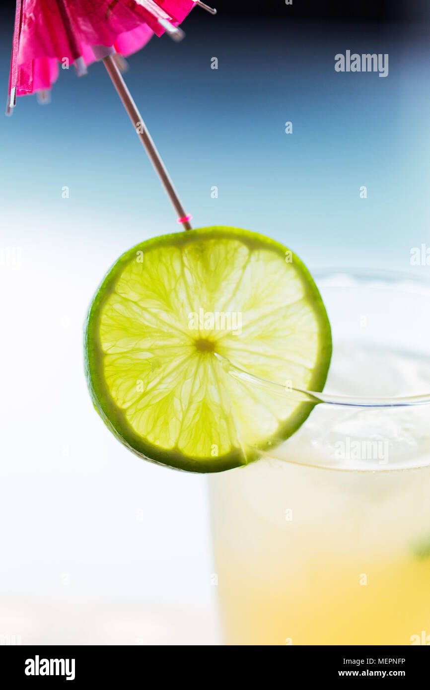 Colorato in giallo drink con fetta di lime e ombrellone Foto Stock