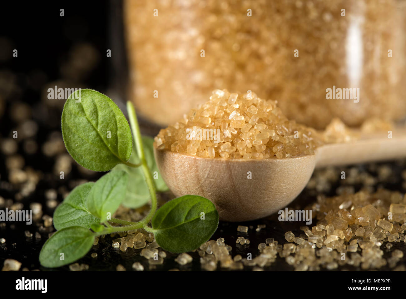 Chiusura del piccolo cucchiaio woode riempito con lo zucchero di canna in ardesia scura Foto Stock