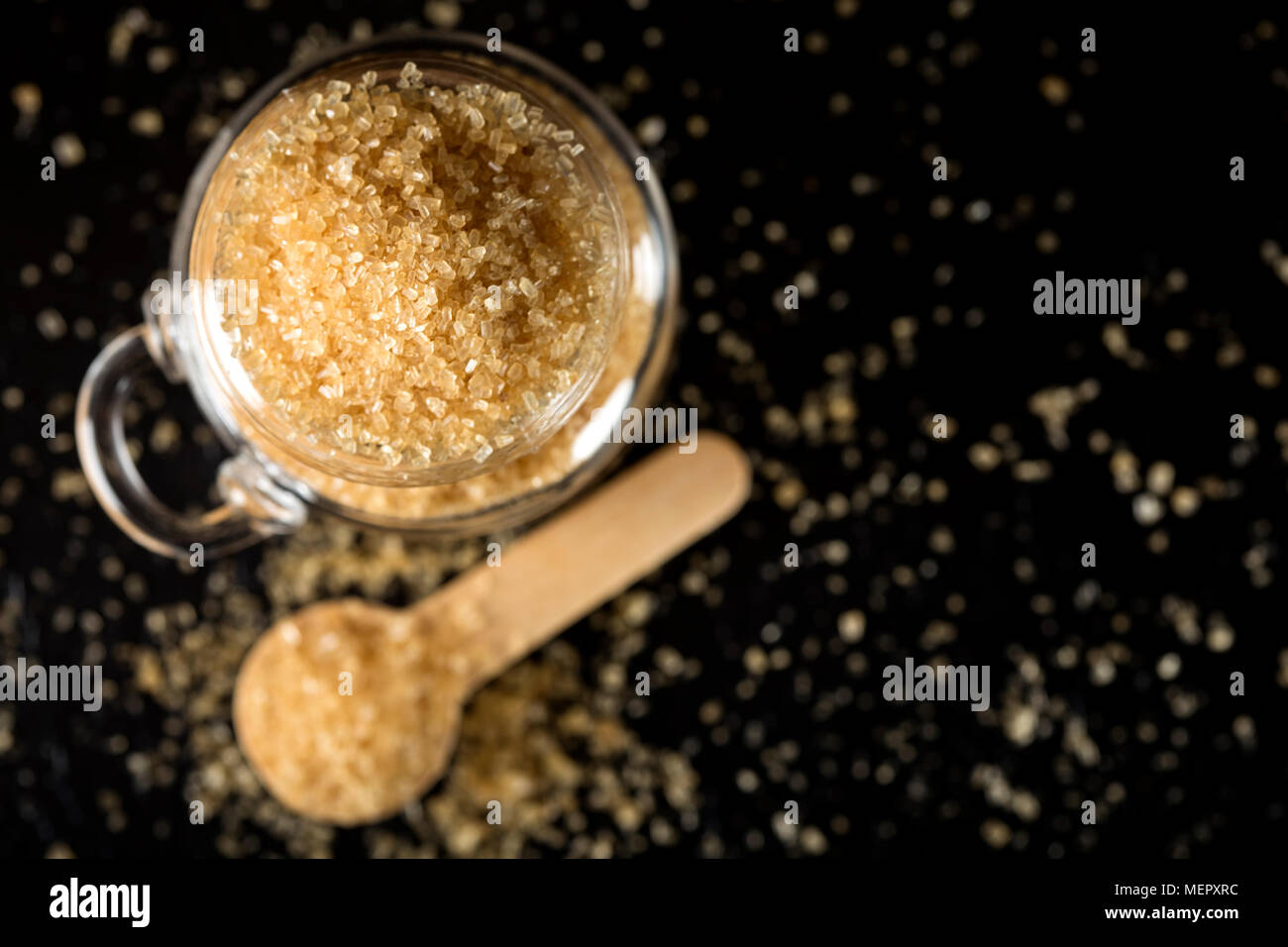 Il vasetto di vetro riempito con zucchero di canna scuro su sfondo di ardesia Foto Stock