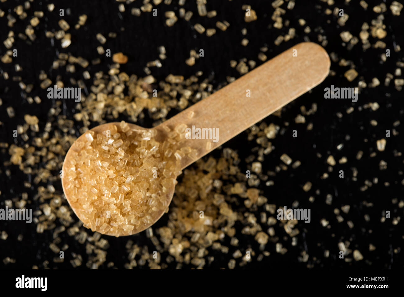 Piccolo cucchiaio woode riempito con lo zucchero di canna in ardesia scura Foto Stock