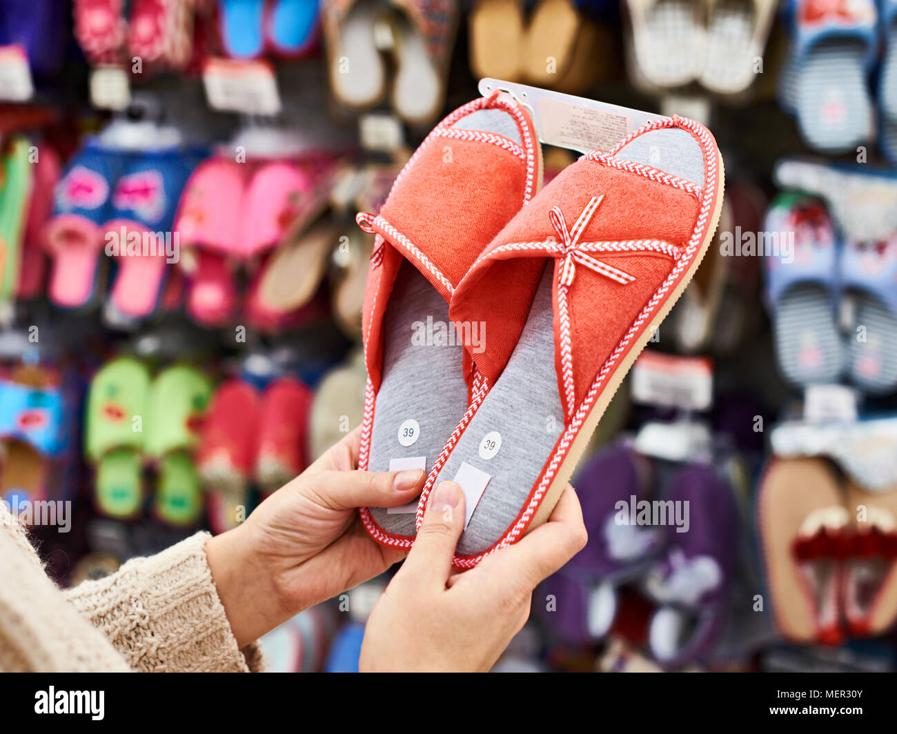 Donna cliente sceglie home pantofole in negozio Foto Stock