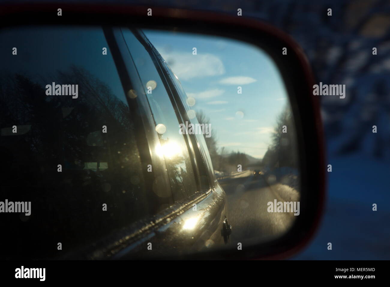 Close up specchio laterale di un auto guidando su una strada di campagna su una soleggiata giornata invernale. Foto Stock