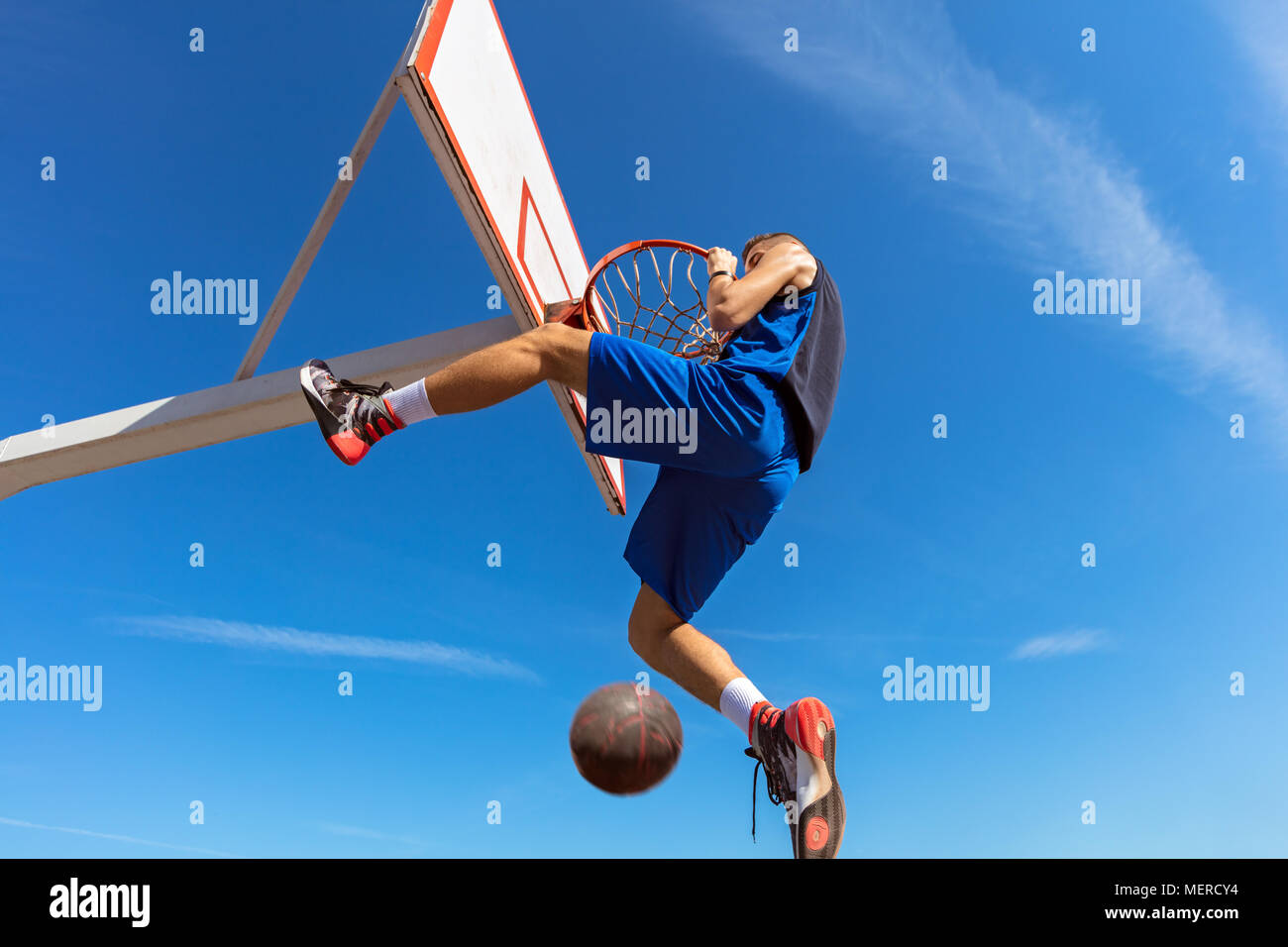 Slam Dunk. Vista laterale del giovane giocatore di basket rendendo slam dunk Foto Stock