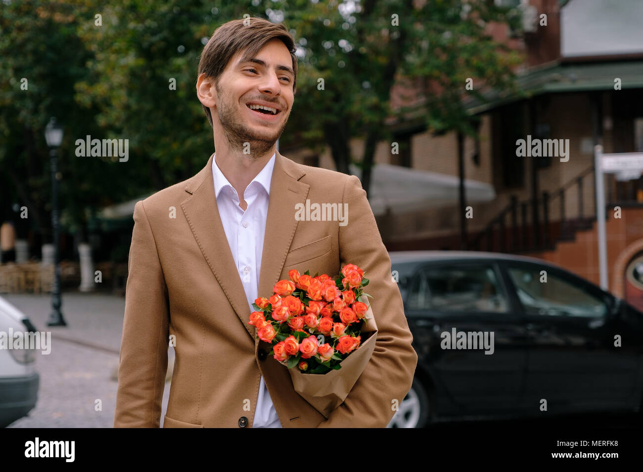 Ritratto di giovane uomo bello sorridente tenendo un mazzo di rose Foto Stock