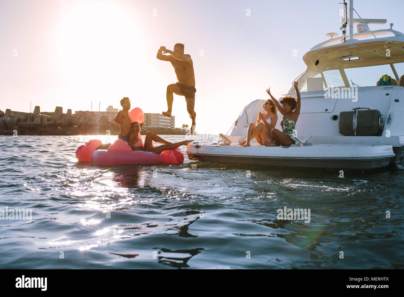 Giovane uomo tuffarsi nel mare di barca con gli amici il tifo. Gruppo di amici avente una grande vacanza di estate. Foto Stock