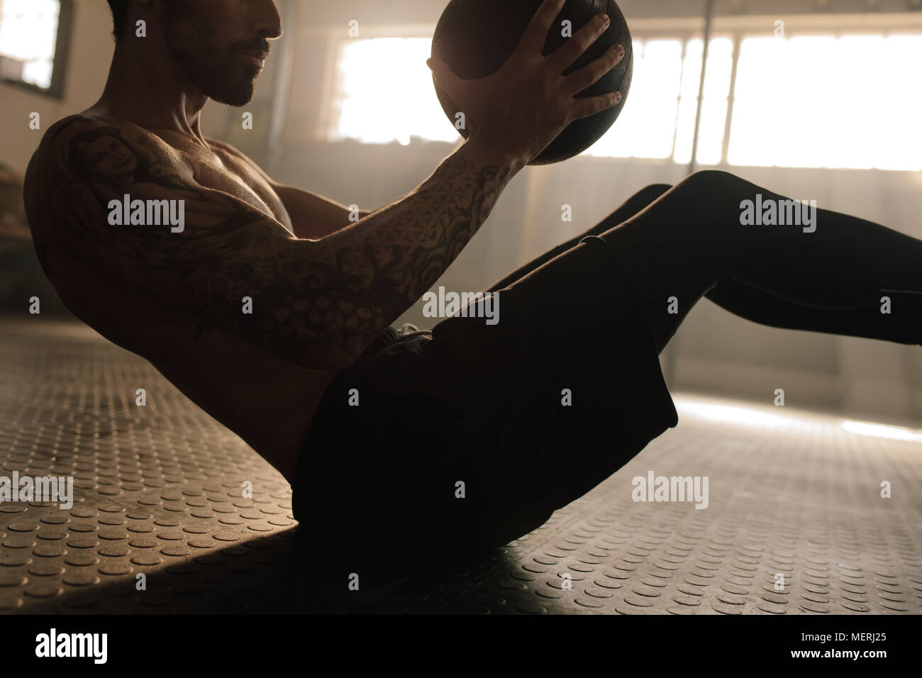 Uomo muscolare esercitando con palla medica in palestra. Giovane uomo facendo allenamento tramite la sfera di fitness. Foto Stock