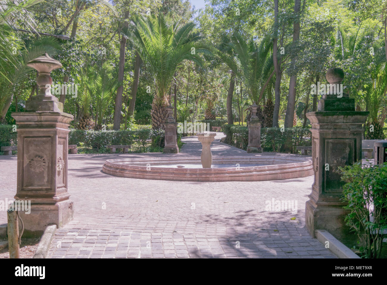 Vista serena di Benito Juarez Parco con alberi, pietra fontana, colonne di pietra e il sentiero in pietra, in una giornata di sole in San Miguel De Allende, Messico Foto Stock