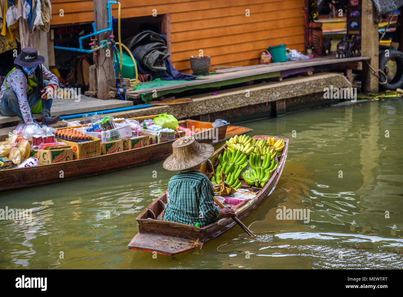 Venditore locale con le banane in un mercato galleggiante in Thailandia Foto Stock