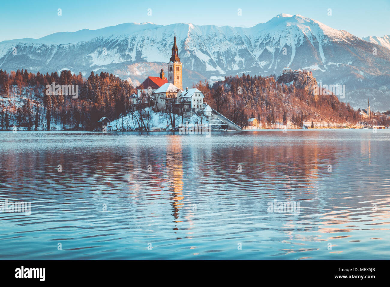 Bellissima vista della famosa isola di Bled (Blejski Otok) presso il pittoresco lago di Bled con il castello di Bled (Blejski grad) e Alpi Giulie sullo sfondo di sunrise Foto Stock