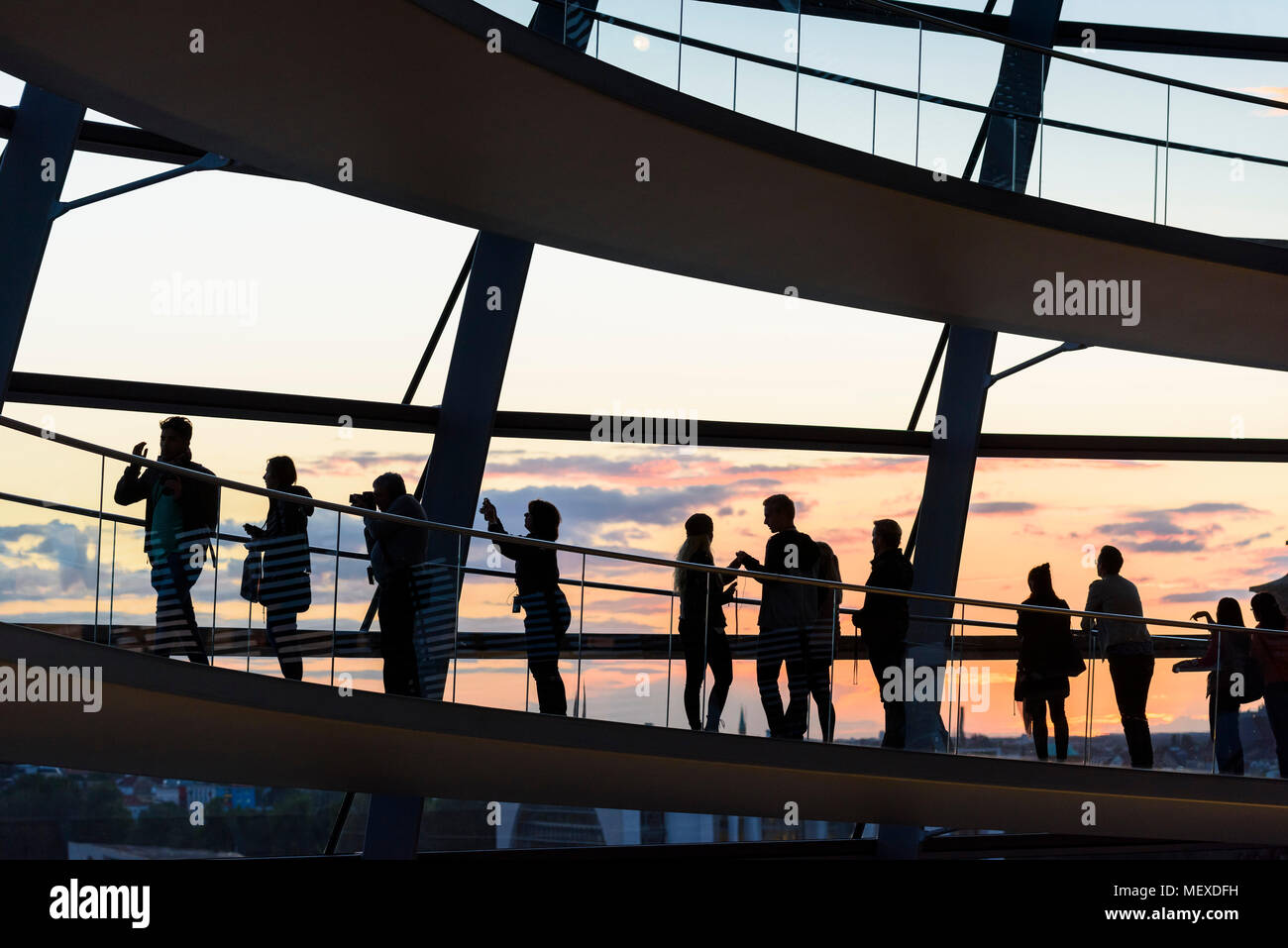 Berlino. Germania. I visitatori della cupola del Reichstag silhoutted contro il tramonto. Foto Stock