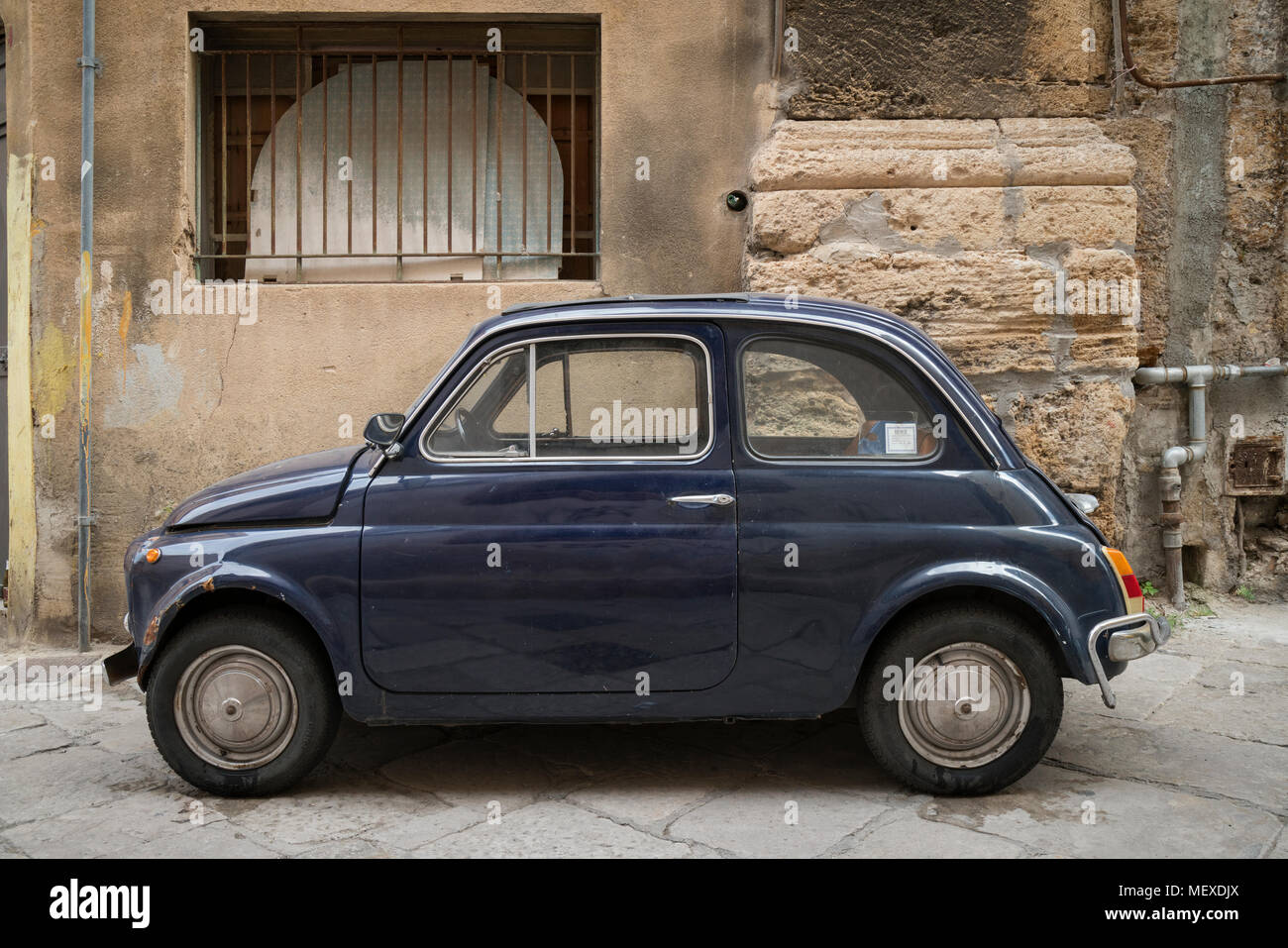 Un classico vecchio blu Fiat 500 parcheggiato in una stradina di Palermo, Sicilia, Italia, un iconico scena italiana. Foto Stock