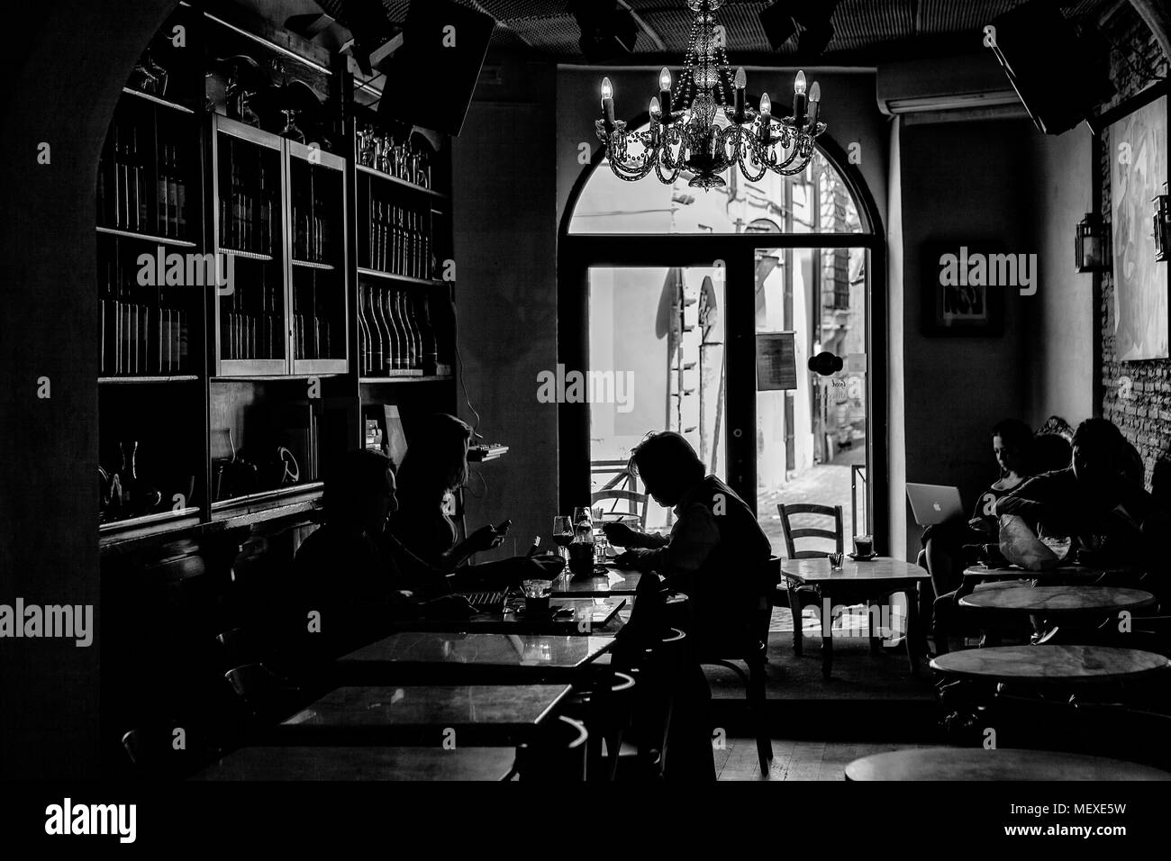 Dark moody interno di un caffè con la gente seduta ai tavoli Foto Stock