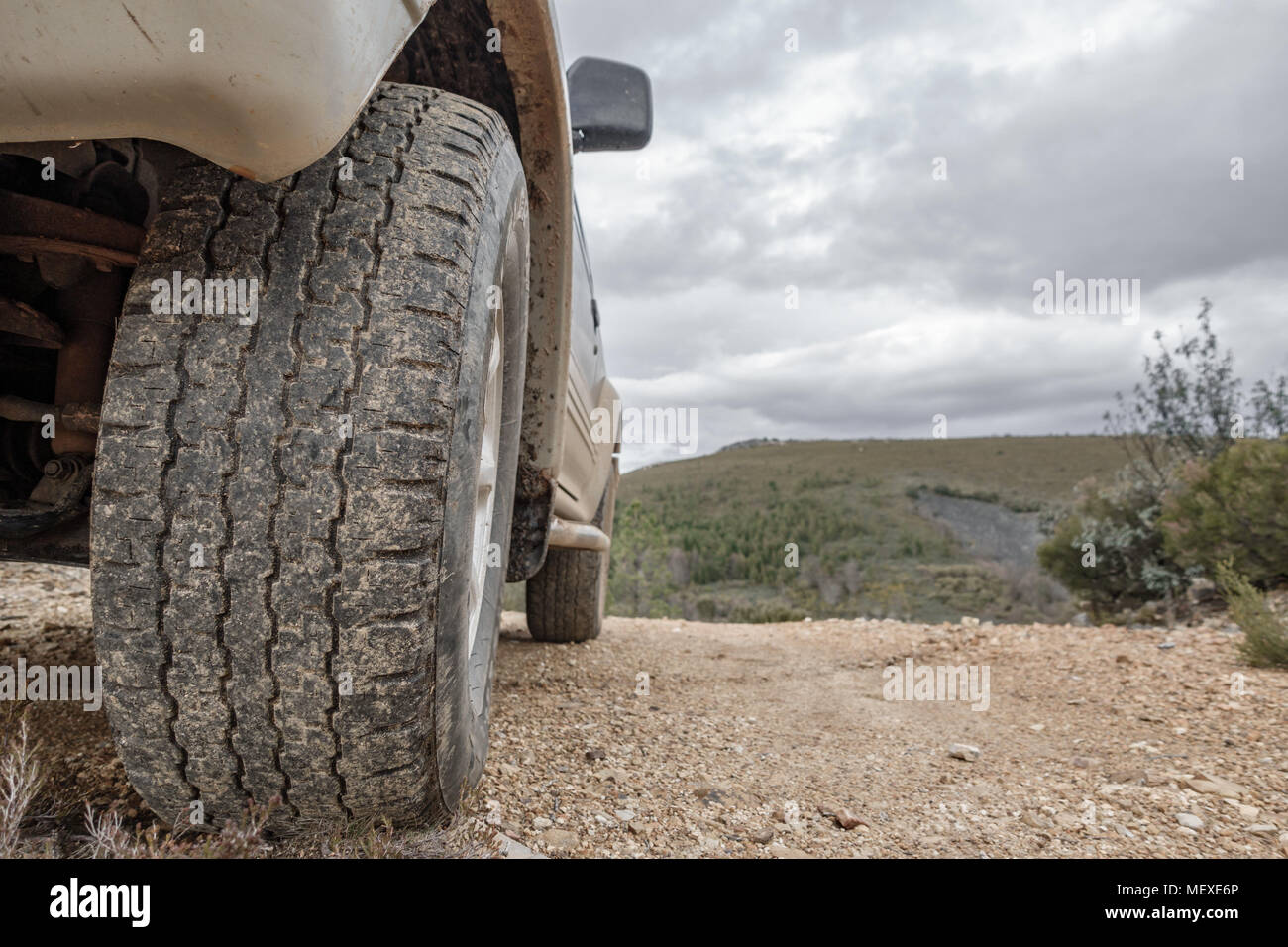 Grande 4x4 auto ruota sorge su sfondo di montagna Foto Stock