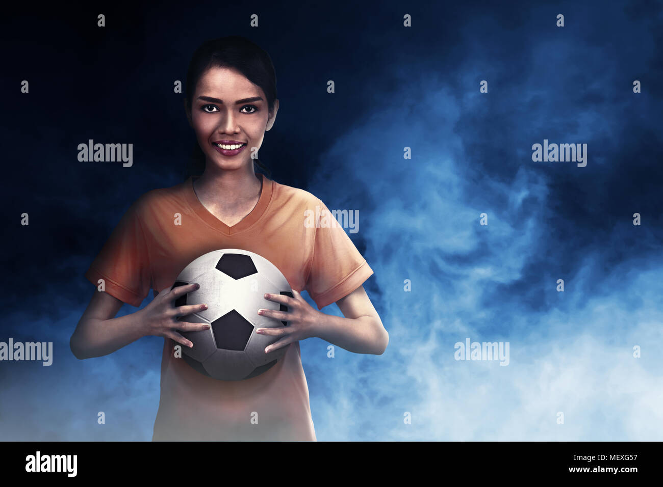 Sorridente calciatore asiatico donna sfera portante sulla sua mano Foto Stock