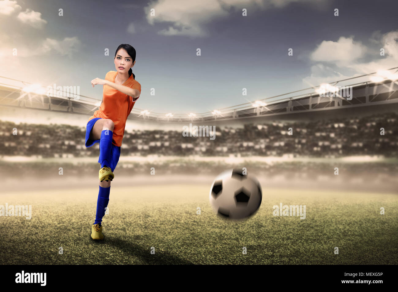 Attraente calciatore asiatico donna calci palla durante il match di Stadium Foto Stock