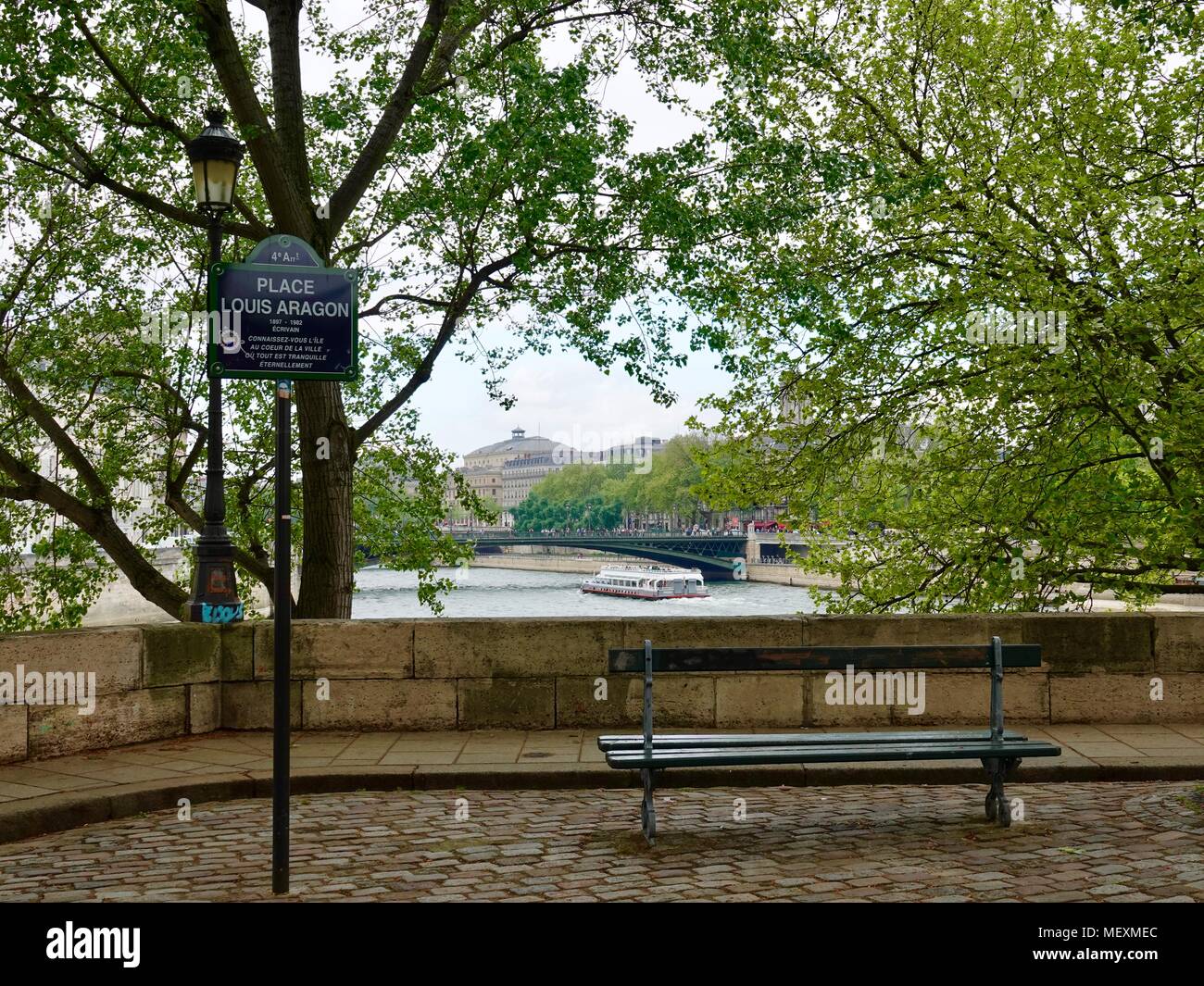 Lone da banco e la barca turistica sul fiume Senna in distanza. Place Louis Aragon, Quai de Bourbon, Parigi, Francia. Foto Stock