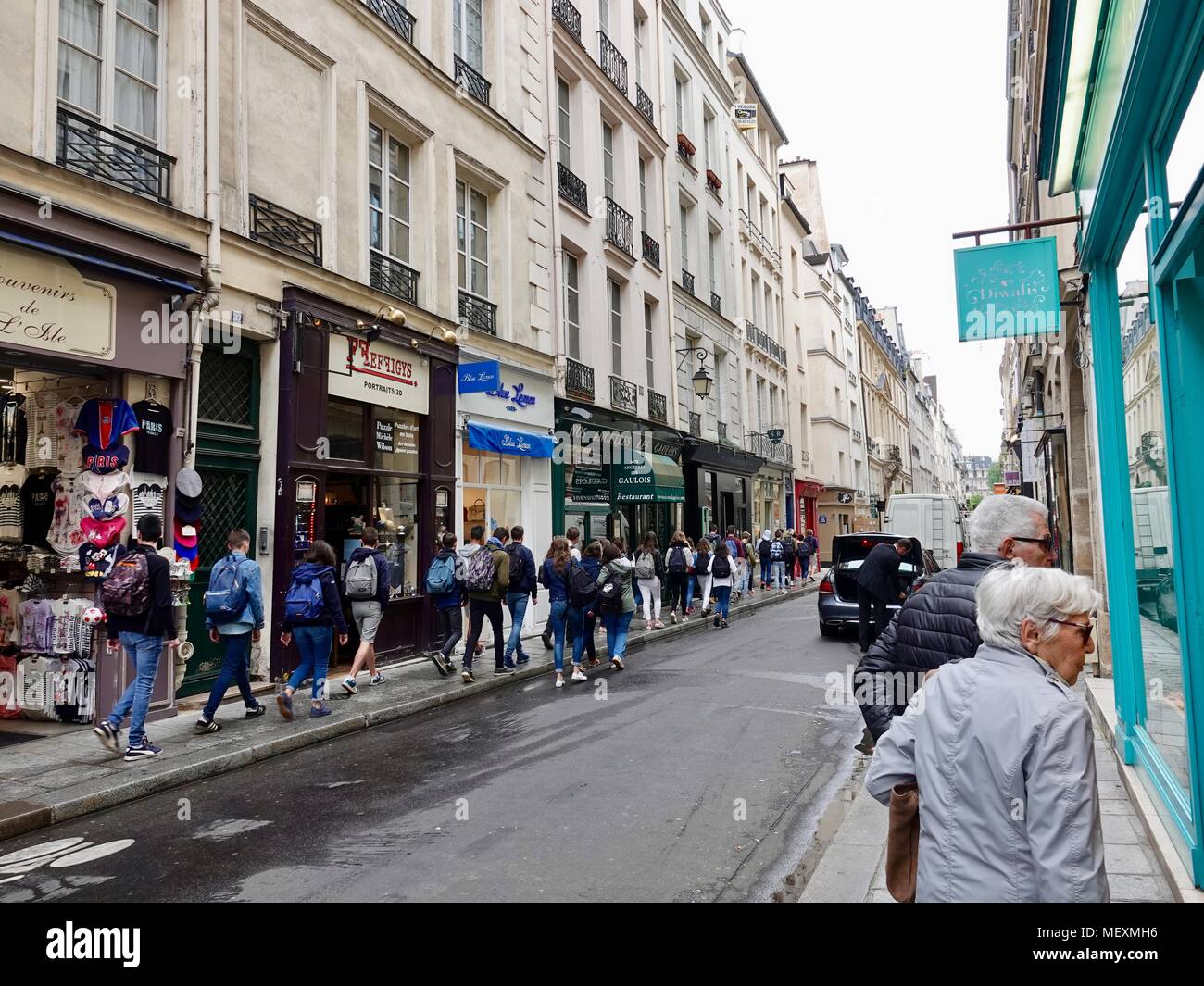 Coppia di anziani negozi di vetro, classe di alta scuola gli studenti in gita passeggiate lungo il lato opposto della strada. Rue Saint-Louis en L'Ile. Parigi Foto Stock