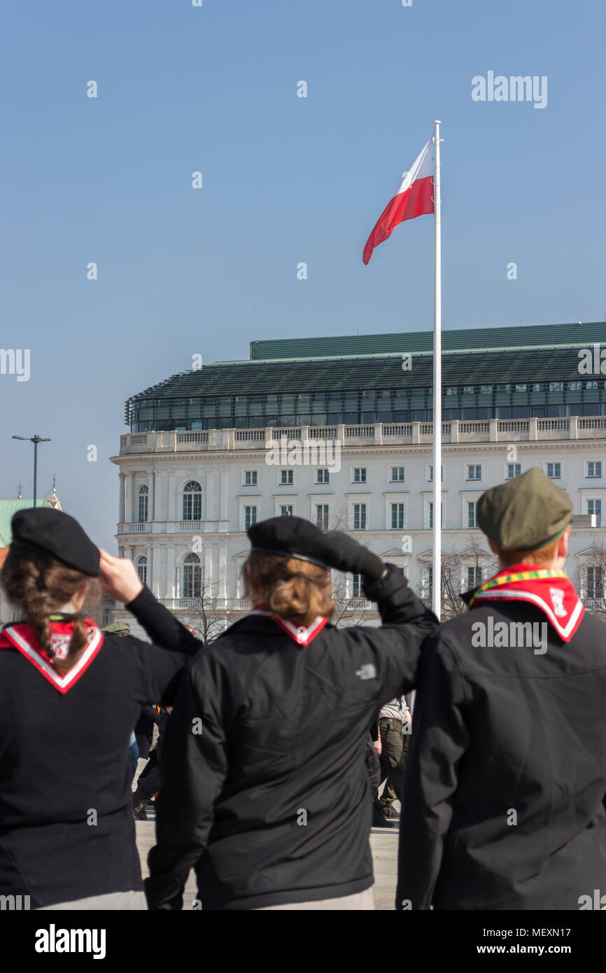 Tre scout saluta davanti a bandiera polacca in piazza Pilsudski Foto Stock