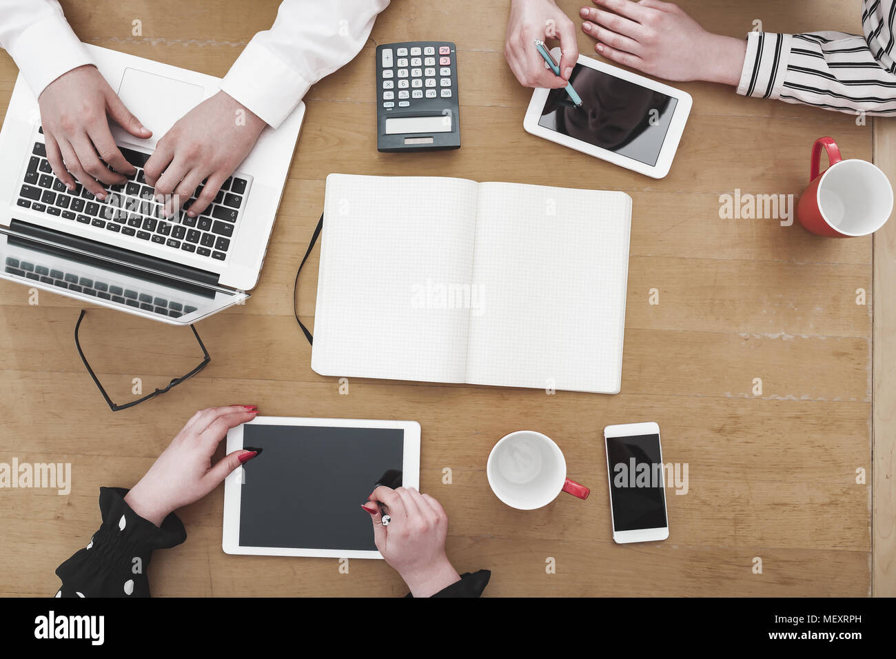 Young business team lavorano insieme come un gruppo sulla scrivania in ufficio con più dispositivi elettronici e carta basata su strumenti Foto Stock