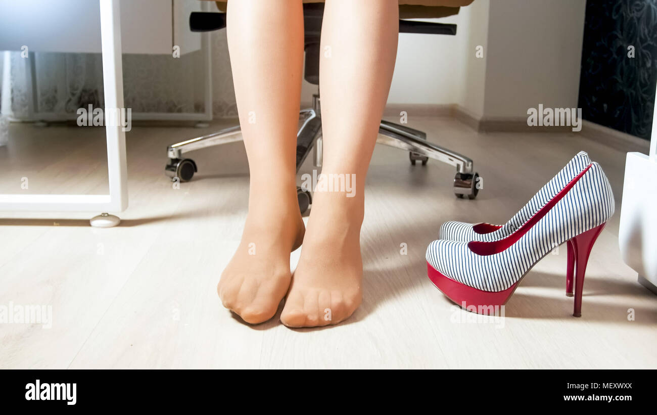 Giovane donna a piedi nudi rilassante dopo di indossare tacchi alti scarpe  in ufficio Foto stock - Alamy