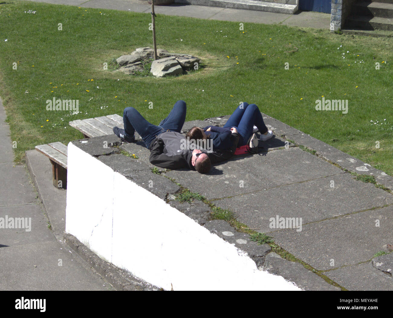 Coppia di mezza età sdraiato addormentato sul terreno godendo il sole primaverile. Foto Stock