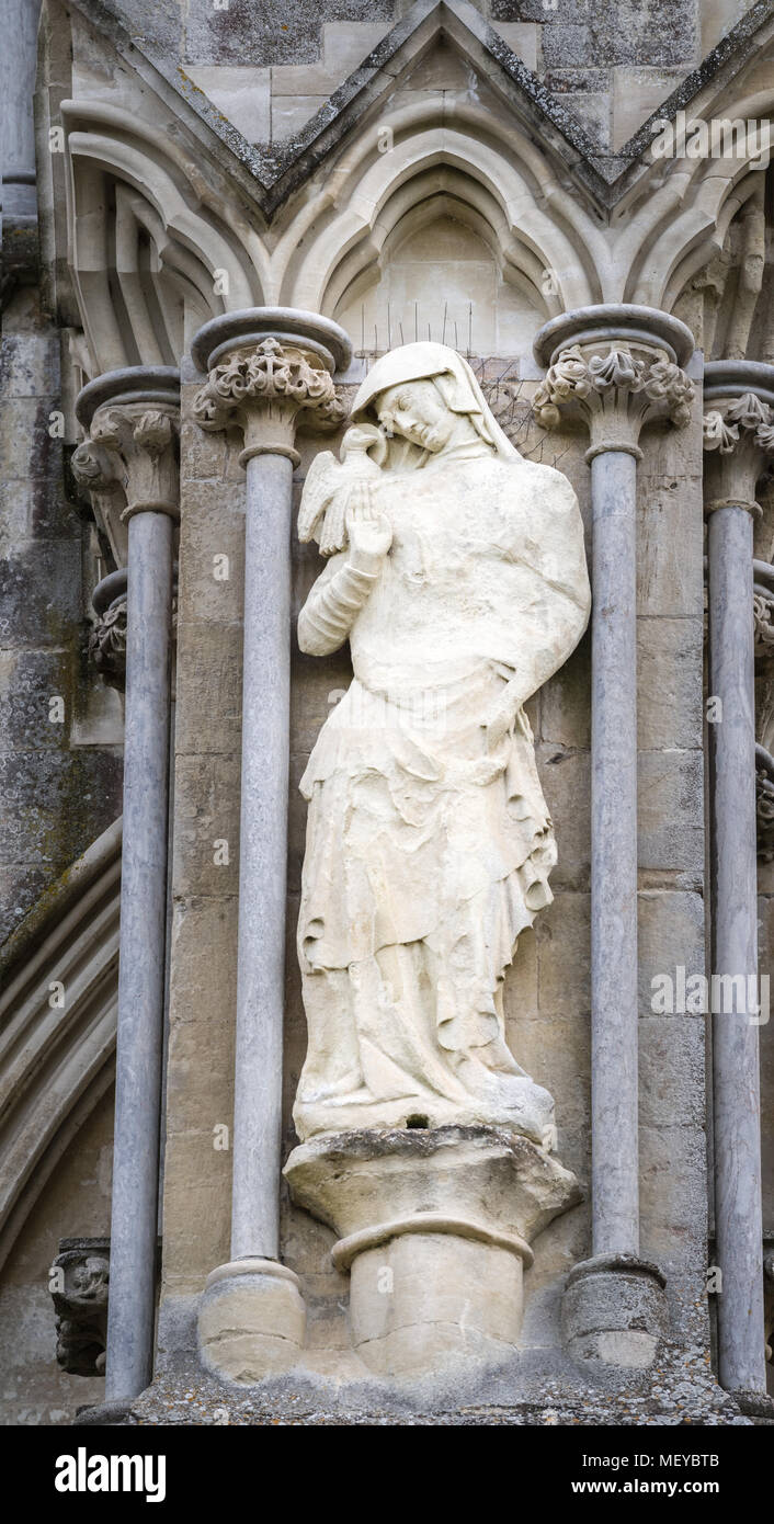 Weathered pietra scolpita la statua di San Giovanni evangelista sul lato esterno la parete ovest presso la cattedrale medievale di Salisbury, Inghilterra. Foto Stock