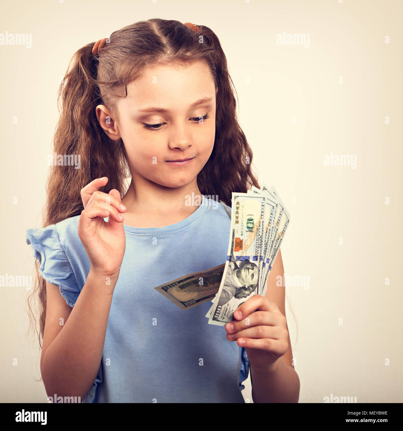 Sorridenti ricca kid girl holding e conte di denaro. Vintage ritratto dai toni Foto Stock