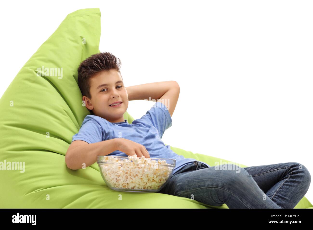 Ragazzo con una ciotola di popcorn seduto su una beanbag isolati su sfondo bianco Foto Stock