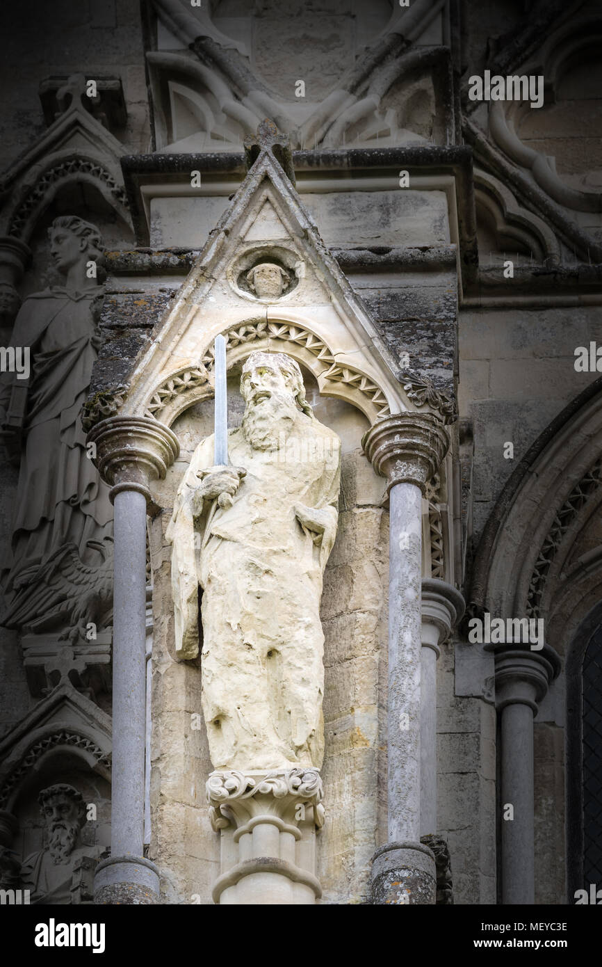 Weathered pietra scolpita la statua di San Paolo evangelista sul lato esterno la parete ovest presso la cattedrale medievale di Salisbury, Inghilterra. Foto Stock