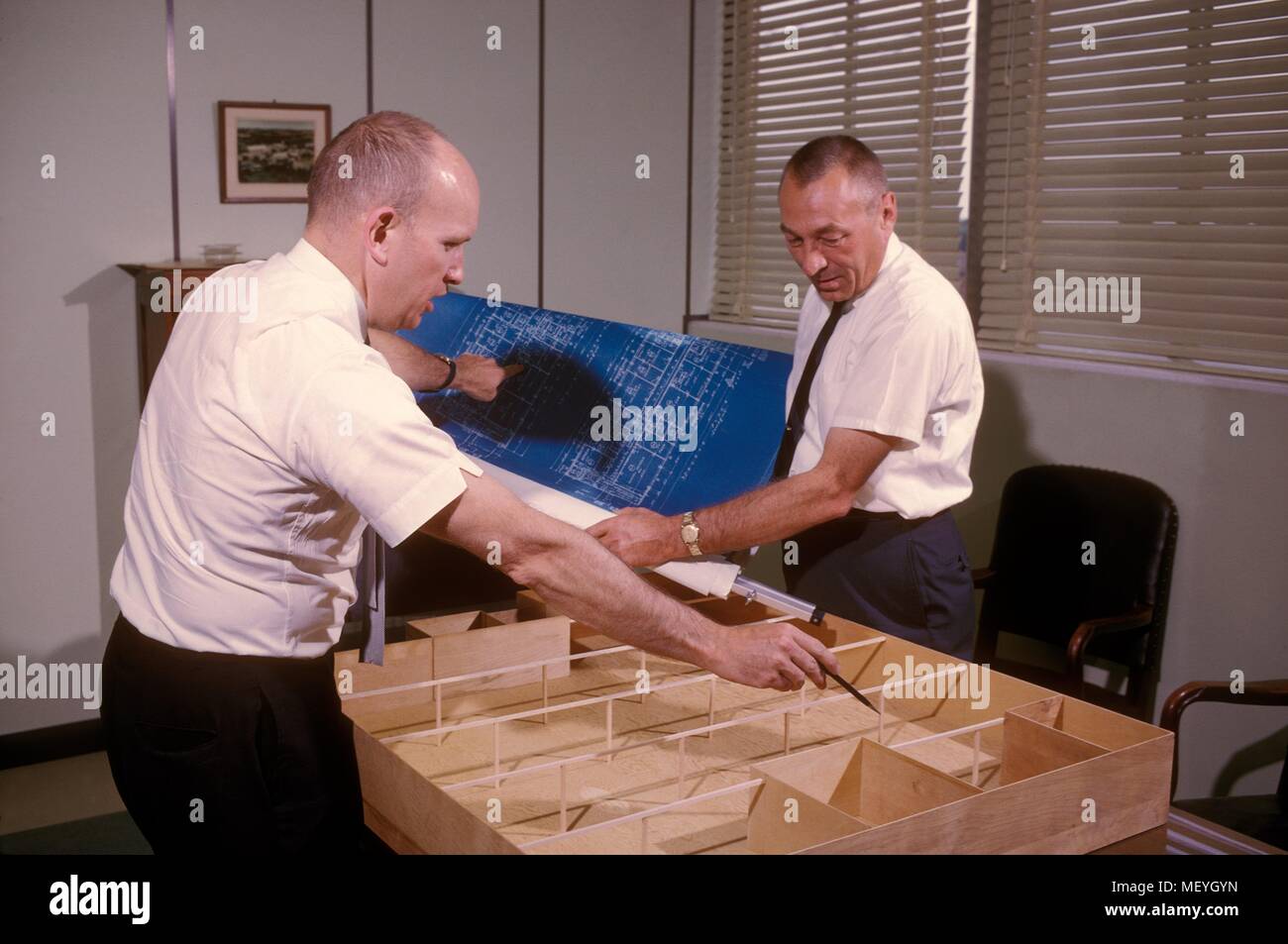 Due centri per il controllo e la prevenzione delle malattie (CDC) ingegneri discutendo piani e di un modello di un nuovo impianto, 1965. Immagine cortesia centri per il controllo delle malattie / James G. Paine. () Foto Stock