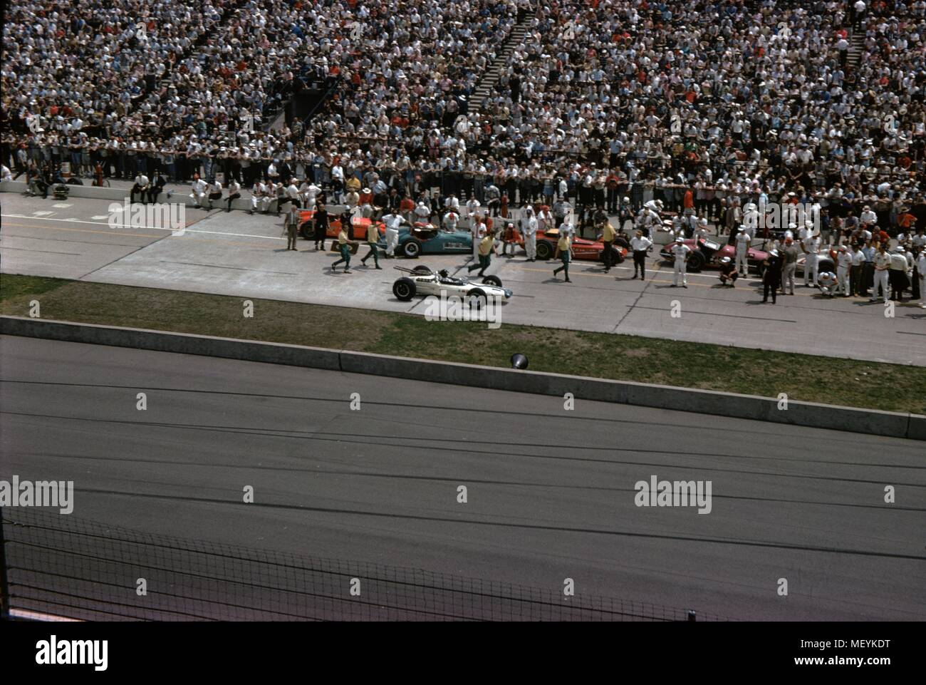 Auto da corsa e gli spettatori sono visibili a Indianapolis 500 gara automobilistica di Indianapolis Motor Speedway di Indianapolis, Indiana, 1965. () Foto Stock