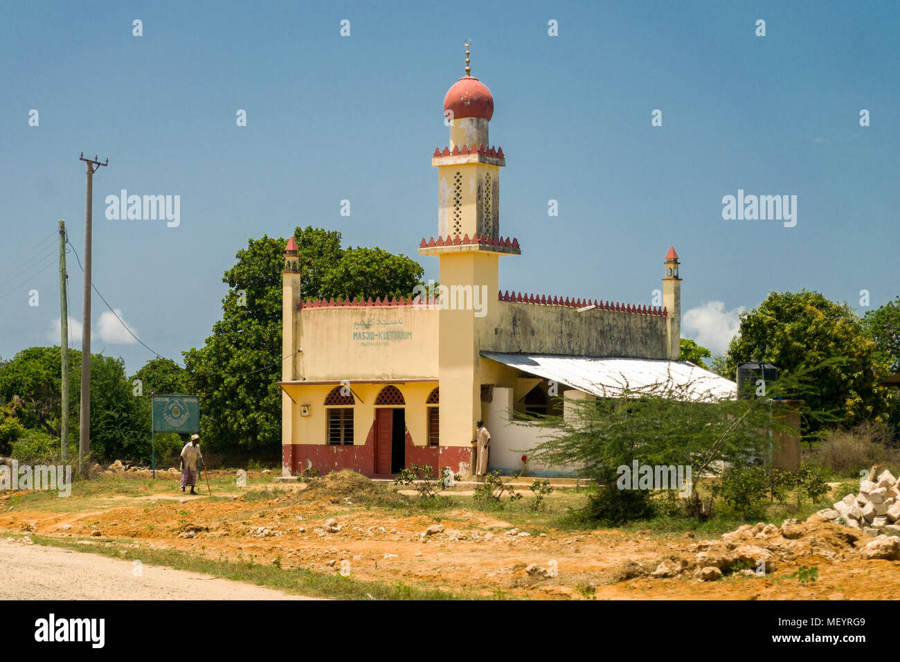 La parte esterna di una piccola moschea musulmana con minareto e due uomini al di fuori in una giornata di sole, Kenya, Africa orientale Foto Stock