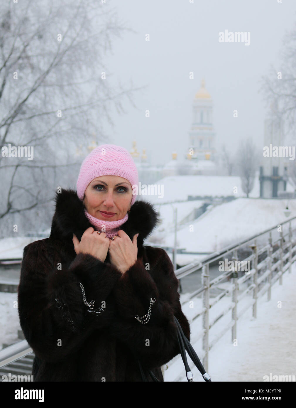 Close-up di foto sorridente e prosperosa donna in pelliccia e anelli d oro sulla neve-ponte coperto. Ritratto d'inverno. Foto Stock