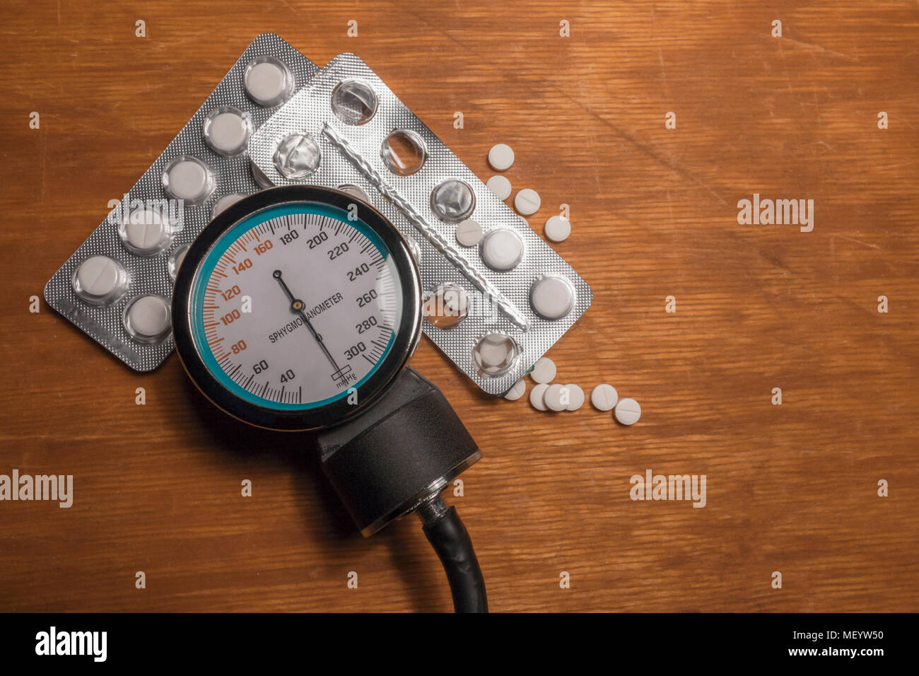 Sfigmomanometro con due alveoli di medicina bianco droga e compresse sparsi sul vecchio tavolo in legno. La scena prima della misurazione di arteriosa blo Foto Stock