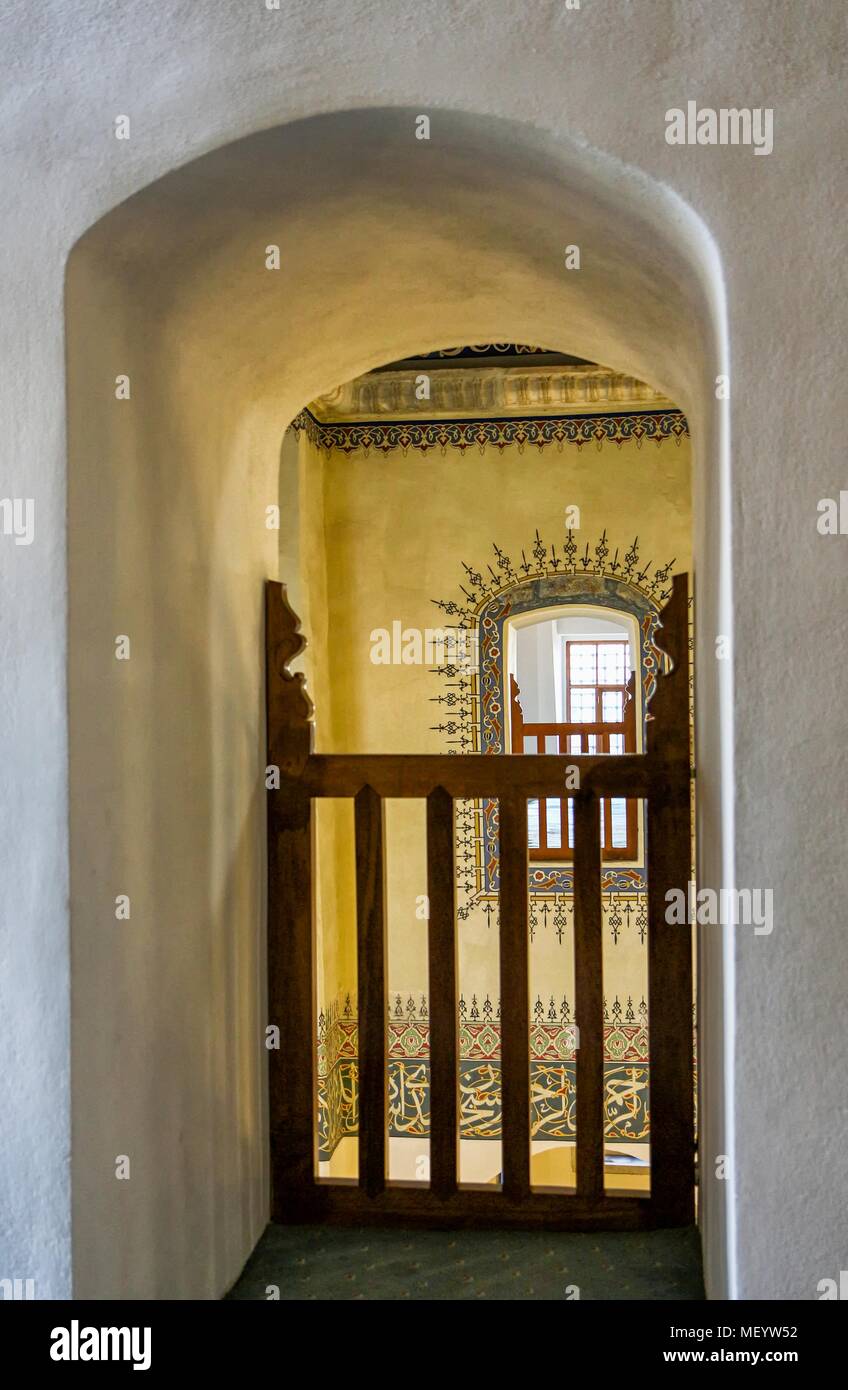 Fotografia di una vista attraverso una apertura con soffitto a volta con una staccionata in legno, guardando oltre ad un simmetricamente corrispondente apertura attraverso, con una cornice decorativa dipinta intorno ad esso, nelle parti superiori della galleria nella Piccola Hagia Sophia moschea di Istanbul, Turchia, 10 novembre 2017. () Foto Stock
