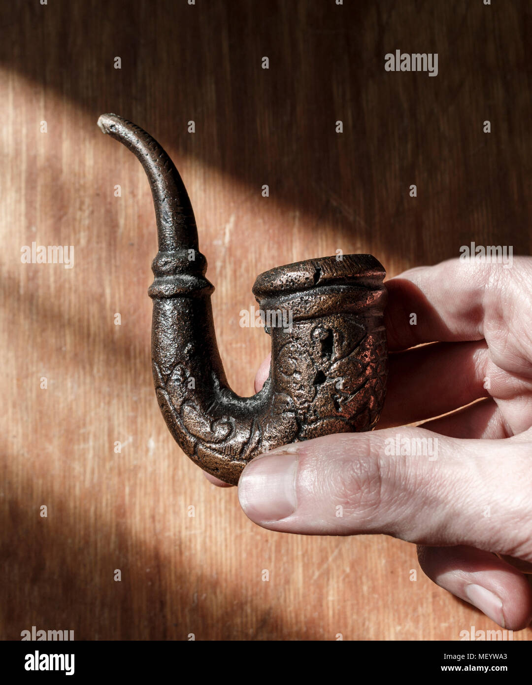 Vecchio fumo di tabacco tubo maschio in mano sull'graffiato lo sfondo di legno Foto Stock