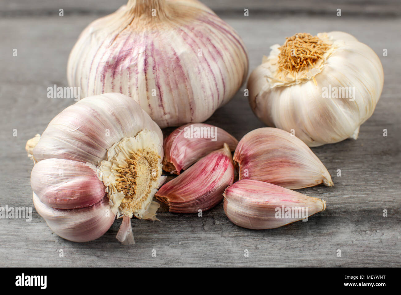 Bulbi di aglio e chiodi di garofano porpora grigio sulla tavola di legno. Foto Stock